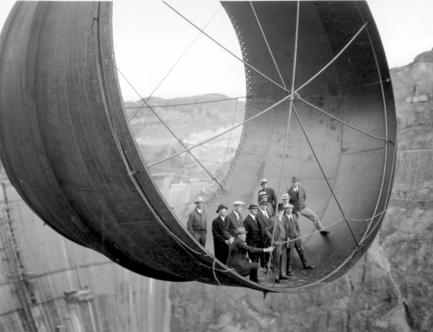 Officials ride in one of the penstock pipes of the soon-to-be-completed Hoover Dam. 1953
