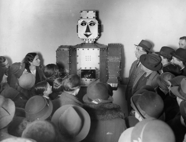 circa 1934: Shoppers admiring a fortune-telling robot at Selfridges Store, London. (Photo by London Express/Getty Images)